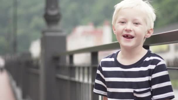 Blonda pojken står av bron och pratar — Stockvideo