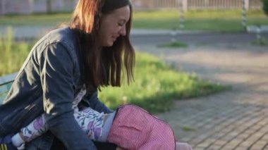 Anne ile küçük bir kız bir bankta oturur. Eğleniyor musun