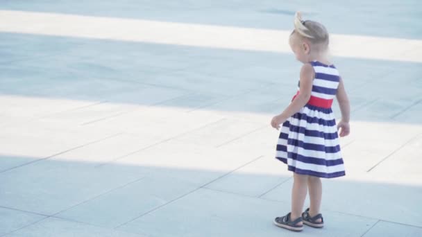 Маленька дівчинка в сукні в смузі повільно бігає по колу — стокове відео