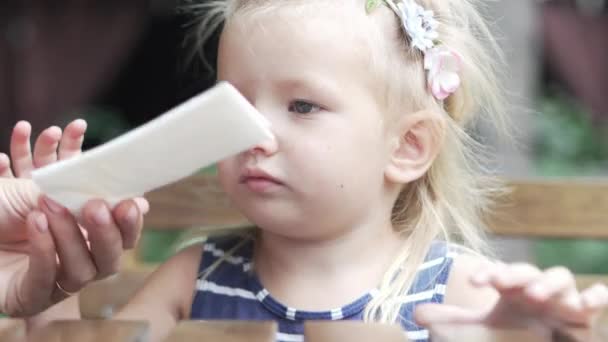 Маленькая девочка сидит за столом в летнем кафе — стоковое видео