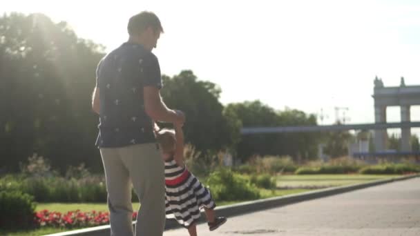 Papa verdreht seine kleine Tochter um sich. Park, Sonnenuntergang — Stockvideo