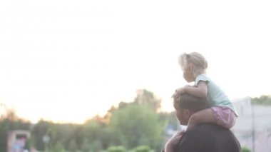 küçük bir kız onu babalar omuzlarında oturuyor