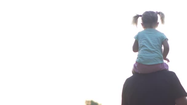 Una niña está sentada sobre los hombros de sus padres. — Vídeo de stock