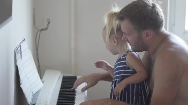 Папа играет на пианино со своей маленькой дочерью. — стоковое видео