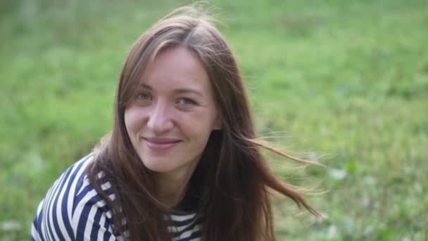 Une femme est assise sur l'herbe et souriante — Video