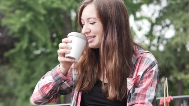 Una mujer está tomando café en un café en la calle. — Vídeos de Stock