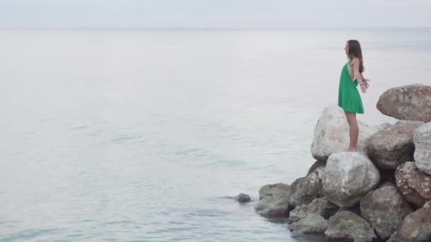 En kvinna står på klippor nära havet. — Stockvideo