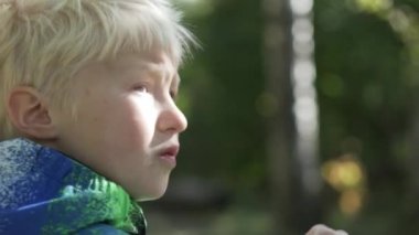 Çocuk albino kabarcıklar darbeler. Çocuk park, serin, dışarıda duruyor. Bir ceket giymiş. Baloncuklar sabun, onları yüzüne getiriyor ve darbeler o tutan onun ellerinde. Tam yüz