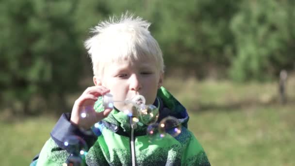 El chico es un albino con burbujas de jabón en las manos. . — Vídeo de stock