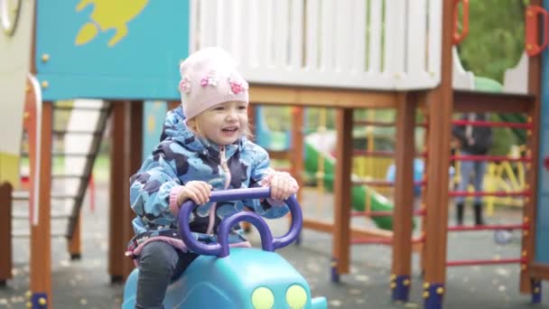 Kleines Mädchen reitet auf Schaukel auf dem Spielplatz. — Stockvideo