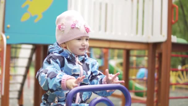 Kleines Mädchen reitet auf Schaukel auf dem Spielplatz — Stockvideo