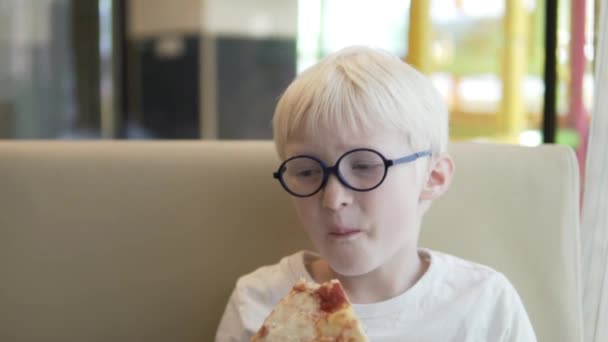 Un niño hambriento come con impaciencia pizza margarita — Vídeo de stock