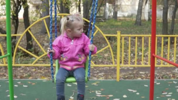 Kleines Mädchen auf einer Schaukel. das Mädchen steigt und fällt — Stockvideo