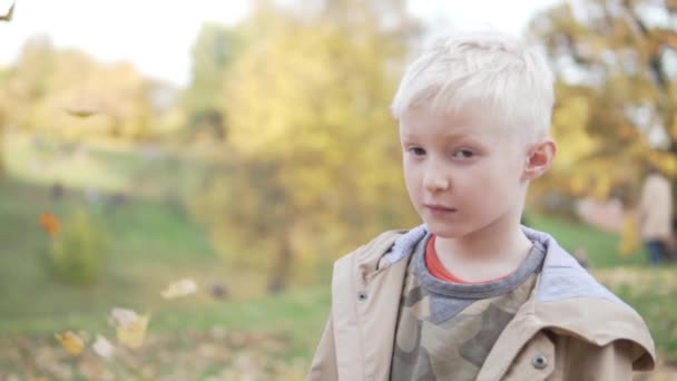 Un beau garçon vomit des feuilles d'automne tombées au-dessus de sa tête 