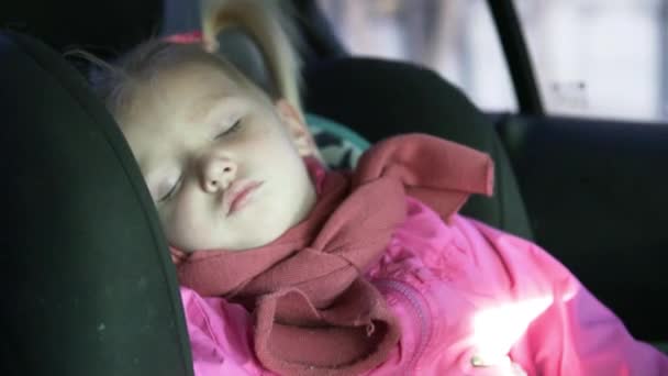 Una niña pequeña monta en un coche en un asiento de coche — Vídeos de Stock