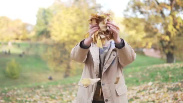 Мальчик стоит в красивом осеннем парке — стоковое видео