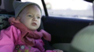 Küçük kız araba koltuğu arabaya biniyor.