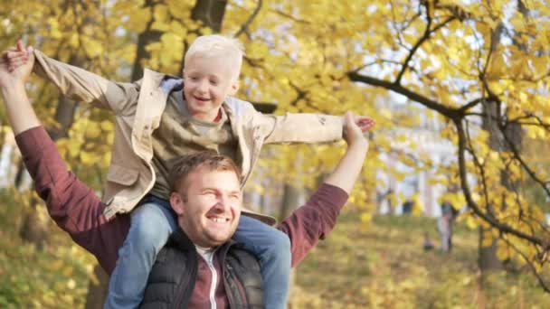 El chico se sienta sobre los hombros de sus papás — Vídeos de Stock