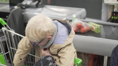 Bir çocuk bir süpermarkette alışveriş bir alışveriş sepeti çeker.