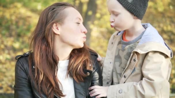 少年と彼の母親は、秋の公園で歩いています。 — ストック動画