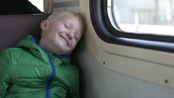 Mignon garçon dans une veste d'automne promenades dans un train électrique — Video