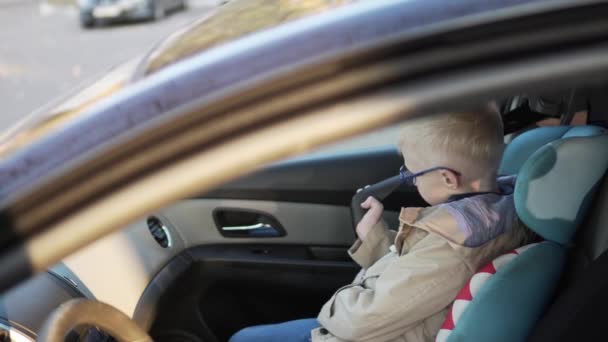 Σοβαρή ξανθό αγόρι κλιπ στο στο αυτοκίνητο. — Αρχείο Βίντεο