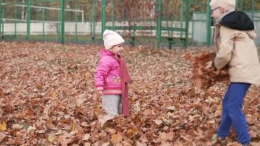 Kardeş Shan bir kucak dolusu düşen sarı yapraklar kız kardeşi atar.