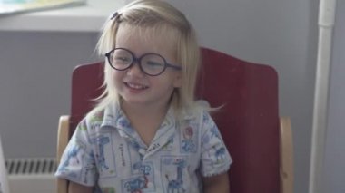 Gözlük ve pijama, küçük bir kız mutfak masasında oturuyor