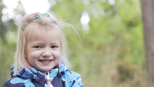 Une petite fille se tient dehors. cheveux balancent le vent .