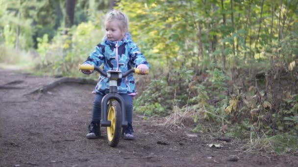 Ett litet barn rider en nedförsbacke från en liten skog bild — Stockvideo