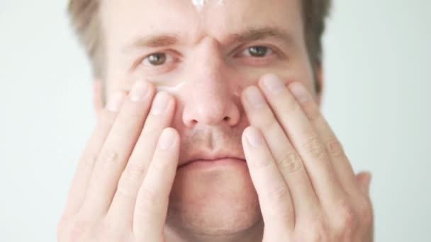 Homem esfrega hidratante no rosto . — Vídeo de Stock