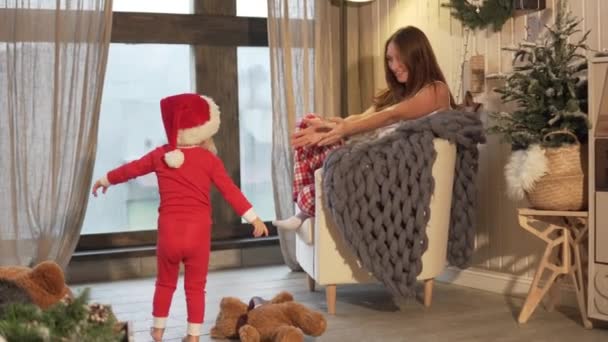 Nieuwjaar. Moeder zit in een stoel. Ze is het dragen van pyjama's van Kerstmis — Stockvideo