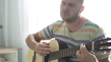 Bir adam gitar çalıyor ve bir şarkı söyler