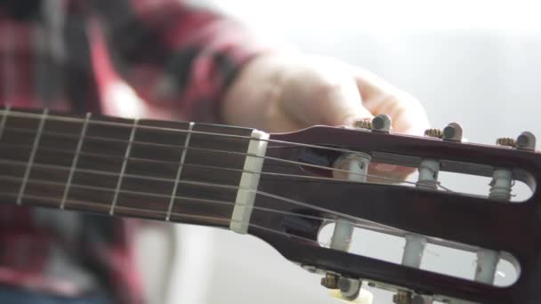 La ragazza con la camicia a quadri accorda la chitarra — Video Stock