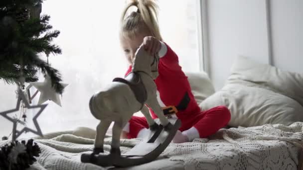 Смішна дівчинка грає в іграшки на новорічну ялинку . — стокове відео