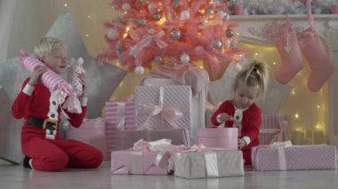 Çocuk pembe Noel ağacın altında oturup.