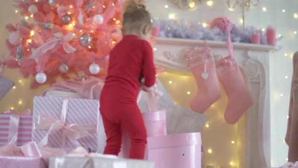 Niña divertida en pijama Santa Claus presenta regalos bajo el árbol de Navidad — Vídeo de stock