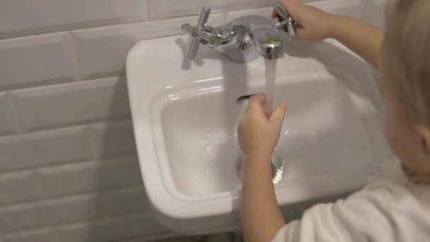 Little girl turns on the water in the childrens washbasins for hands. — Stock Video