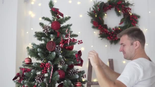 Um homem veste uma árvore de Natal — Vídeo de Stock