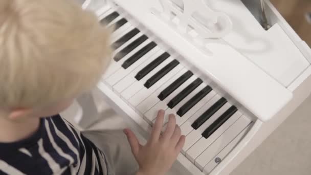 Chico rubio juega en los niños retro piano de color blanco — Vídeos de Stock