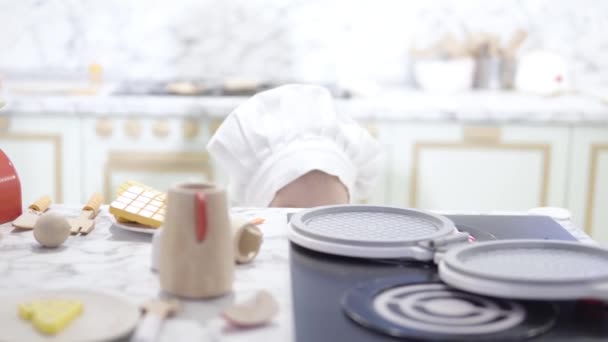 Una Niña Con Sombrero Chefs Esconde Detrás Una Cocina Infantil — Vídeos de Stock