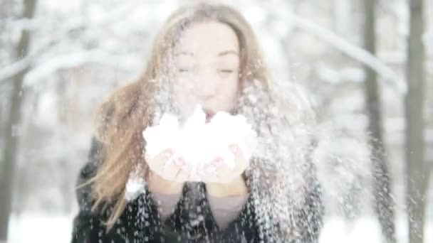 Een jonge vrouw houdt van sneeuw in haar handen. — Stockvideo