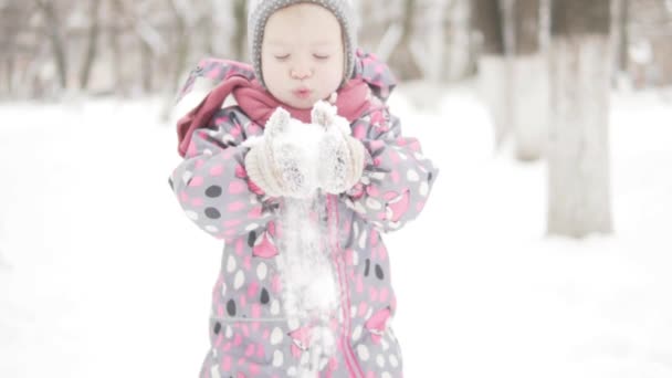 Una niña estudia la nieve mientras camina en el parque — Vídeos de Stock