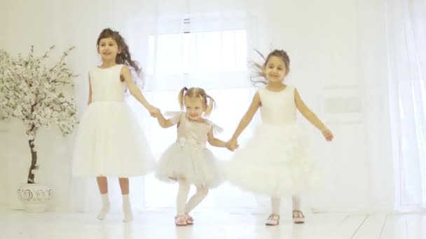 Три красивые маленькие девочки держатся за руки и танцуют на сцене — стоковое видео