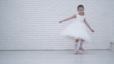 Küçük güzel kızın önünde fotoğrafçılar holiday adlı dönüyor. Çocuk kabarık beyaz bir elbise giyiyor. Konuk önünde bir balerin gibi döner. Düğünde şirin bebek.