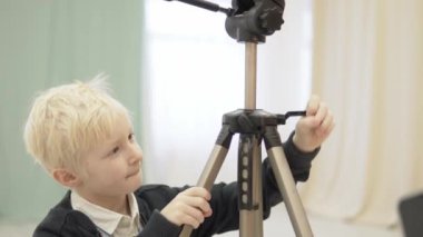 Yakışıklı çocuk bir tripod fotoğrafçı için ayarlar.