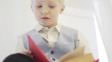 Sarışın bir çocuk kalın bir kitap okuyor