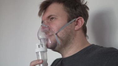 A serious man breathes in a mask on his face.