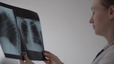 Kadın doktor hastanın bir fotoğrafını dikkatlice inceler.