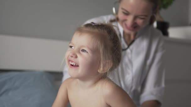 Jeune beau docteur écoute une petite fille avec un stéthoscope — Video